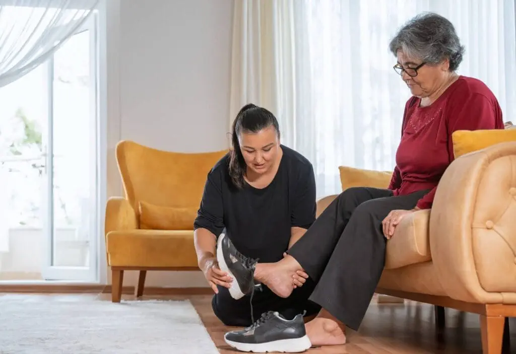 senior woman getting help putting on shoes