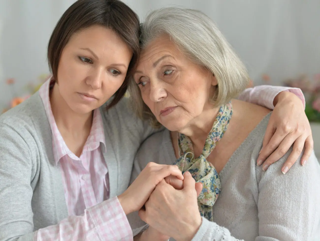 A mother and daughter embrace each other as they have an emotional discussion about dementia care.