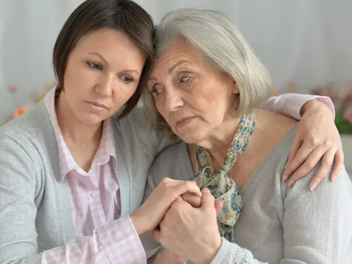 A mother and daughter embrace each other as they have an emotional discussion about dementia care.