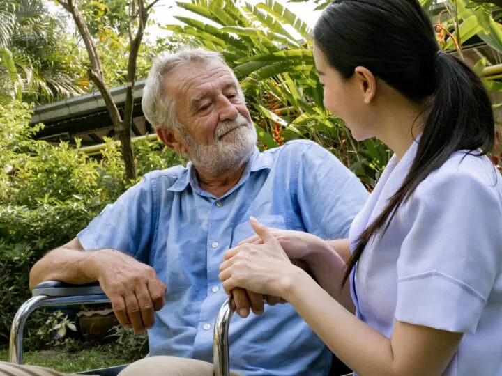 A caregiver trained in trauma-informed care clasping hands with her dementia patient.