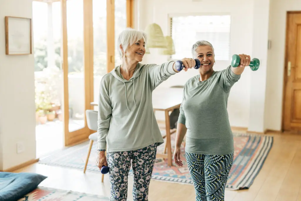 Two women lifting free weights and practicing mobility exercises for seniors at Central Baptist Village.
