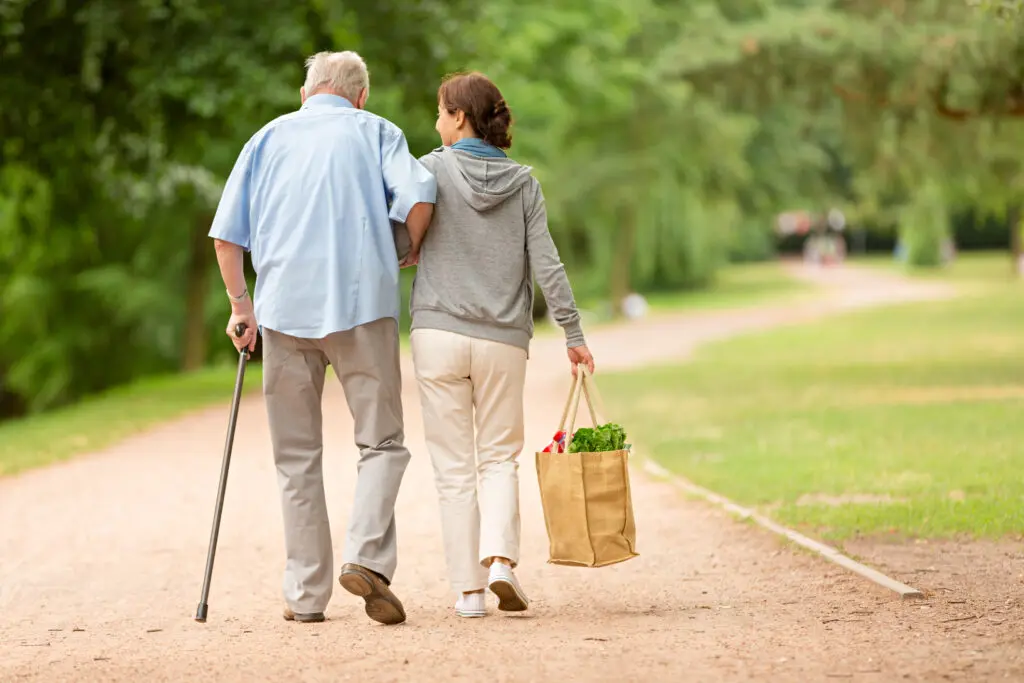 Senior man getting assistance from woman who is carrying groceries