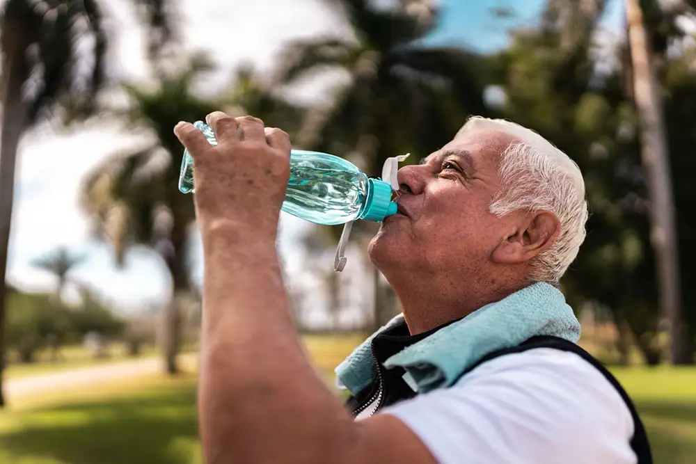a senior man drinking water while out for a jog