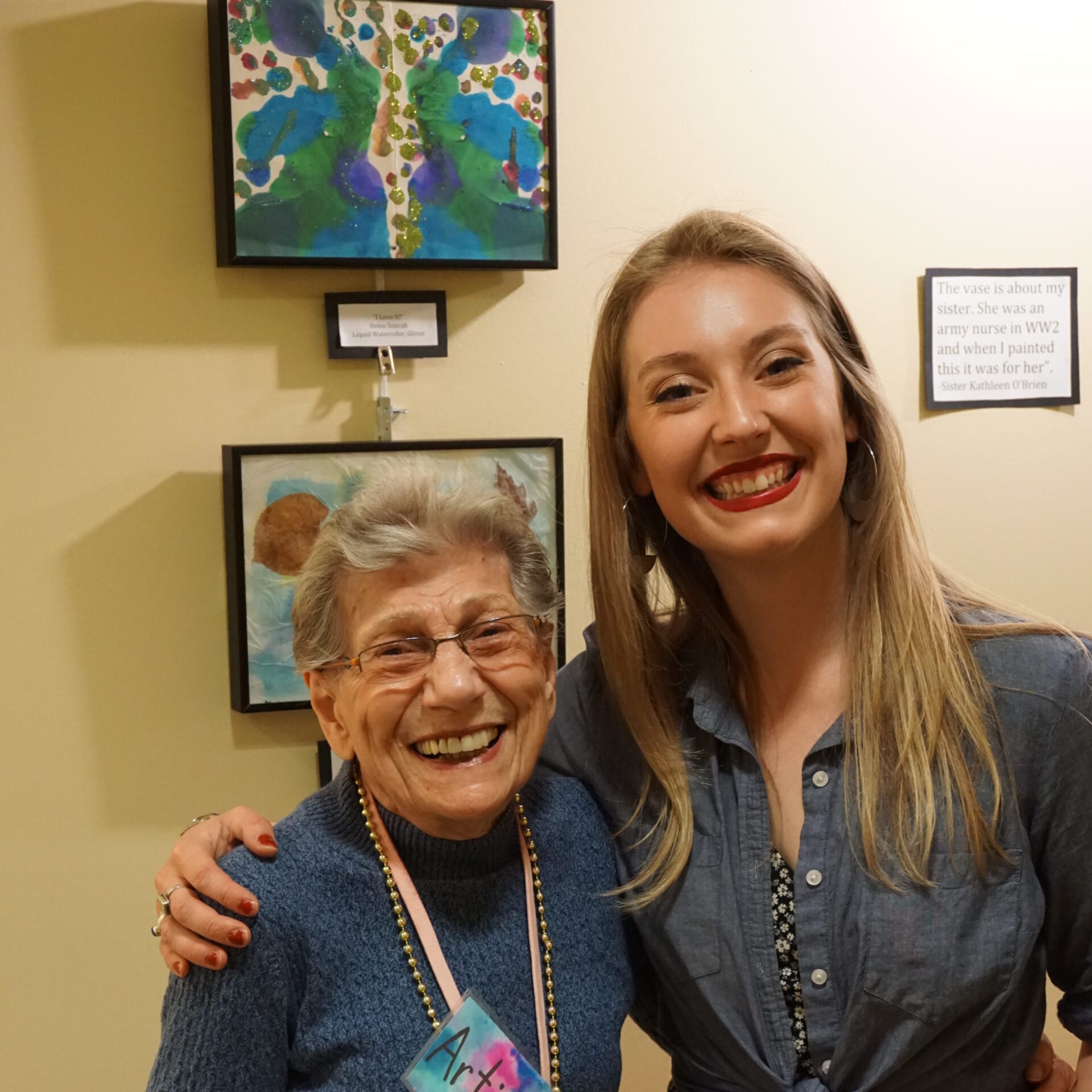 Casie Pax and a CBV resident with the art from their OMA art program for seniors