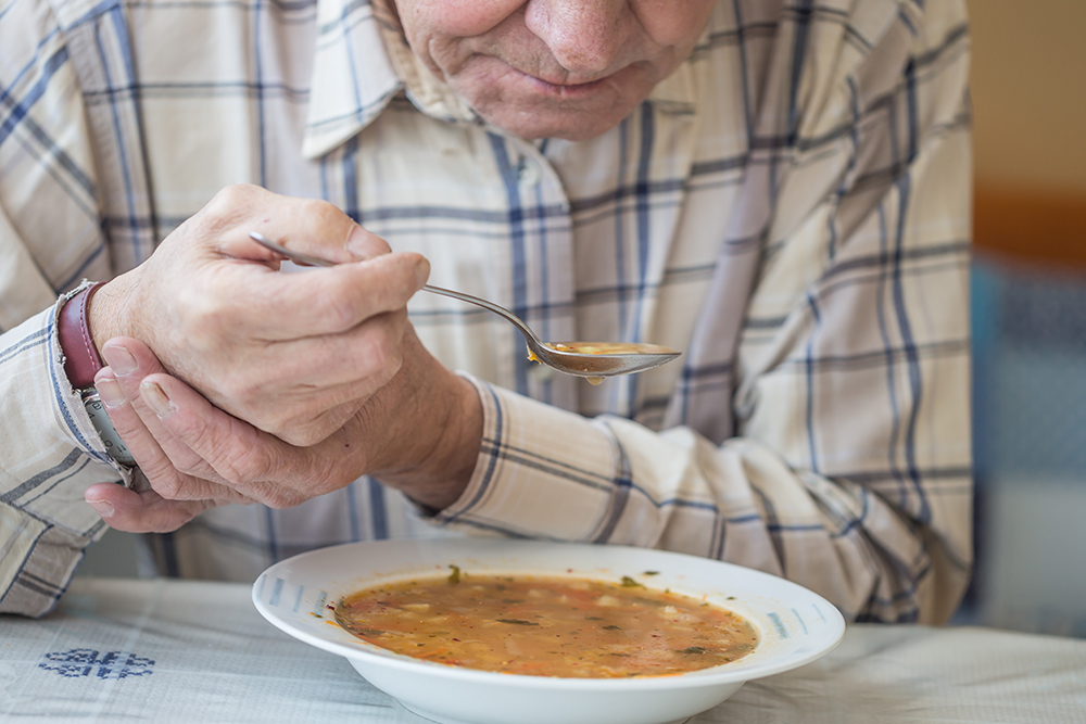 Man with Parkinson's and movement disorder eating soup