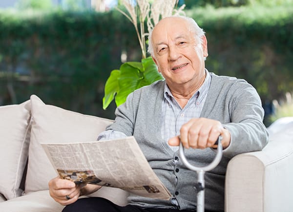 Resident at memory care facility going through relocation stress syndrome reading a newspaper and settling in.