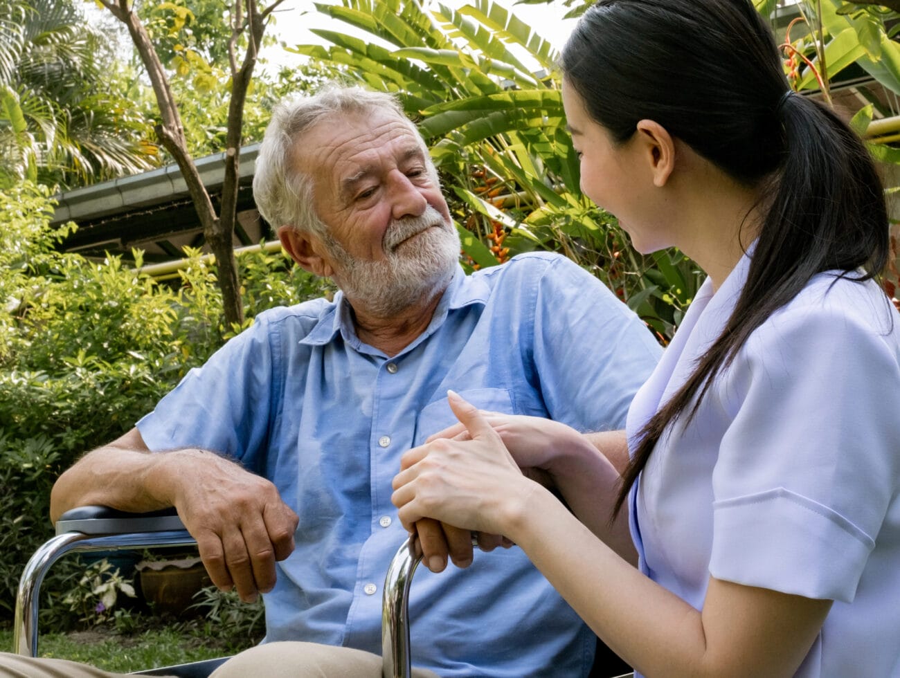 A caregiver trained in trauma-informed care clasping hands with her dementia patient.