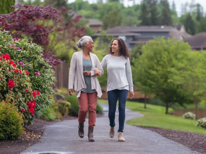 a senior woman taking a walk outside with her adult granddaughter