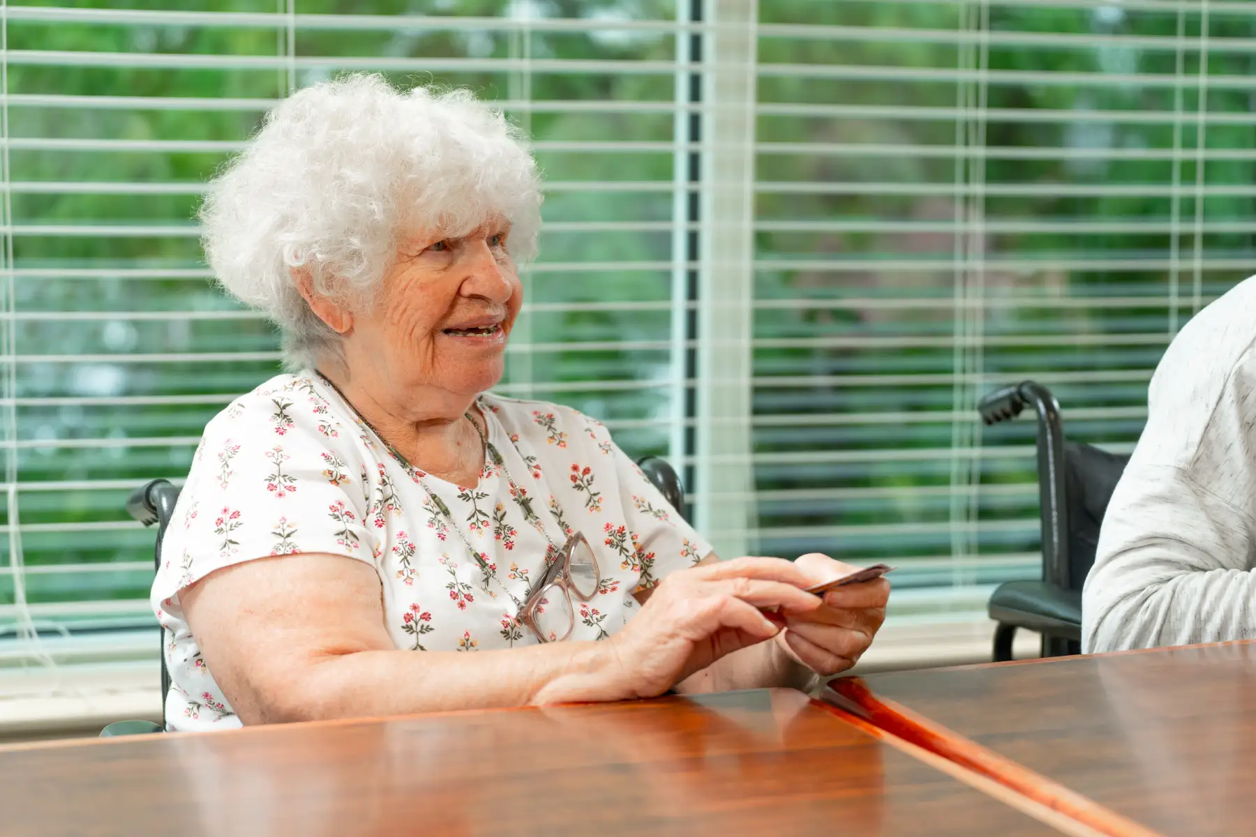 a senior woman playing a card game at a table