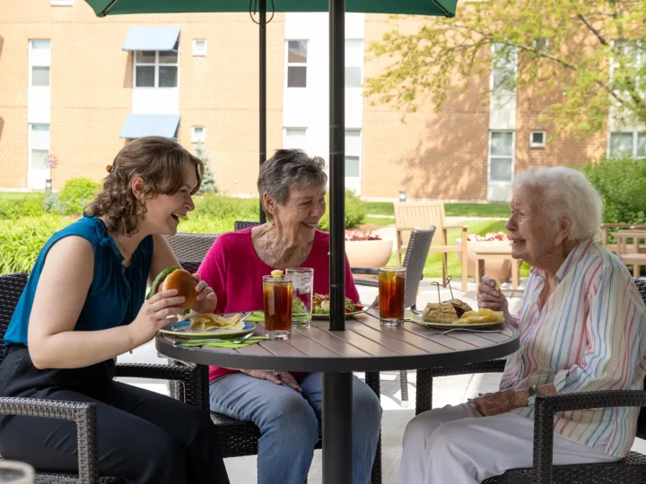 Resident dining outdoors with her visiting family