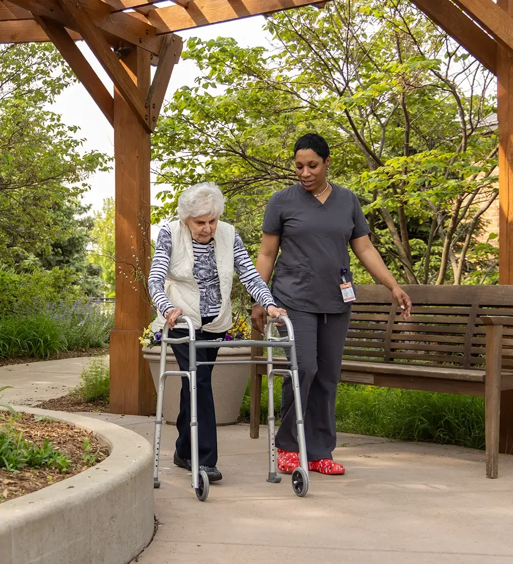 Senior woman with a walker outdoors with her caregiver