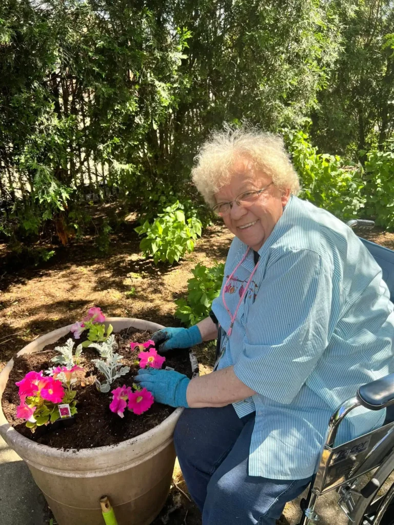 An elderly woman sitting in a wheel chair while gardening flowers. Showing the different levels of care in assisted living at Central Baptist Village in Illinois.
